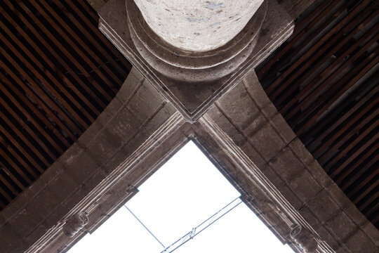 Vista a detalle de unos entre columna y arcos de cantera gris. Captura horizontal. 