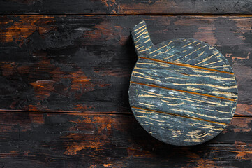 Old dark cutting board on brown wooden table.  Dark background. Top view. Copy space