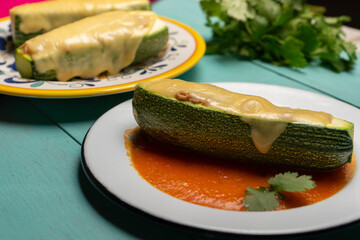 Stuffed zucchini with tuna and melted cheese on turquoise background