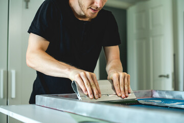 Cropped view of artisan working with squeegee on screen printing machine 