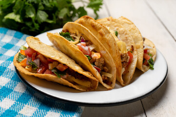 Mexican hard-shell tacos with meat and fresh sauce on white background