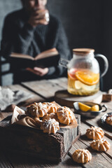 Woman is reading and Hot tea with fresh grapefruit on wooden tablet. Healthy drink, Eco, vegan.