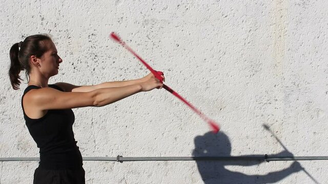 A young girl, a circus performer, spinning Poi on the street, improving her skills.
