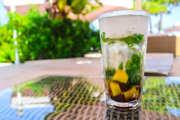 Ice mojito cocktail with lemon and mint on the terrace of the bar. Alcoholic drinks. Relaxation and party time. Copy space for text., selective focus