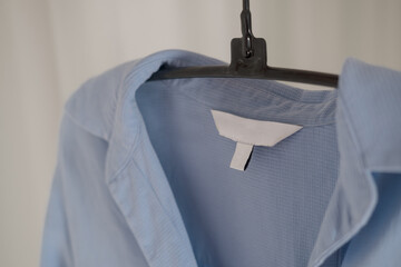 Clothing label on ligh blue fabric. Fashion brand name mock up, closeup 