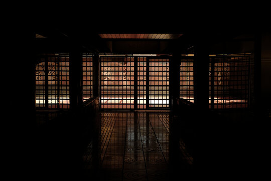 Dark interior of a prison and a barred exit gate.