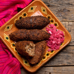 Mexican kibi with meat and onion on wooden background