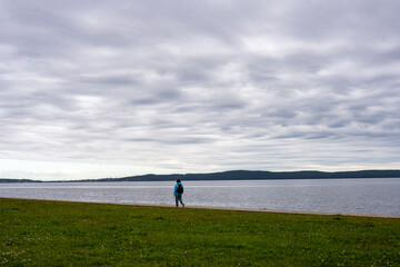 woman with orange hair and in a blue jacket resting on the embankment by the lake