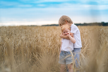 Little girl and boy playing and laughing in the field of grain