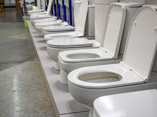Showcase with toilets. Sale in the plumbing store of toilet bowls of different models.
