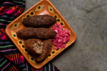 Mexican kibi with meat and onion on dark background
