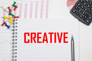 CREATIVE inscription on a notebook against the background of calculator charts, paper clips and pens