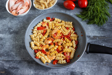 Shrimps with Fusilli pasta and vegetables in a pan . Asian food creative concept. View from above.