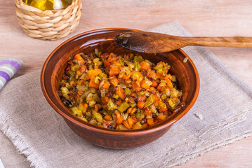 Fried vegetable bases for carrot and celery onion dishes - mirepoix or soffritto in a clay bowl on a wooden table, rustic style