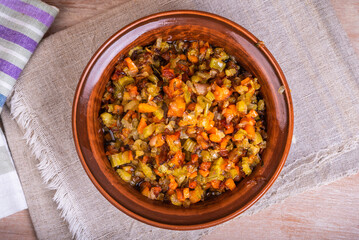 Fried vegetable bases for carrot and celery onion dishes - mirepoix or soffritto in a clay bowl on a wooden table, rustic style, top view