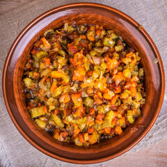 Fried vegetable bases for carrot and celery onion dishes - mirepoix or soffritto in a clay bowl on a wooden table, rustic style, top view