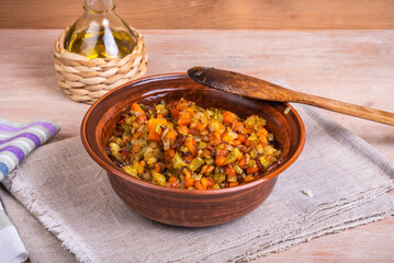 Fried vegetable bases for carrot and celery onion dishes - mirepoix or soffritto in a clay bowl on a wooden table, rustic style