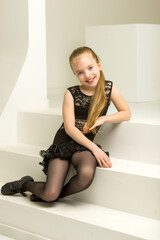 Little girl in a dance costume is sitting on the stairs.