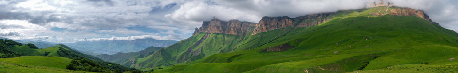 Obraz na płótnie Canvas mountains above green meadows under a blue sky