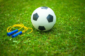 White soccer ball and jump rope for sports on the green grass