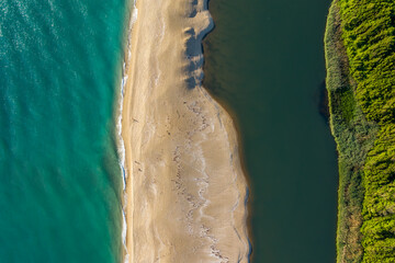 Beautiful sandy beach surrounded by sea waves on one side and on the other by the waters of a river that flows into the sea, the mouth of Veleka River at the Black sea coast, Bulgaria