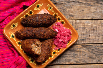 Mexican kibi with meat and onion on wooden background