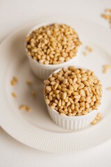 two cups with peeled pine nuts on a white background