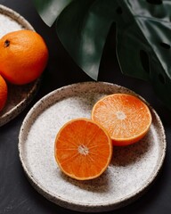 on the table next to a large plant are oranges, whole and cut