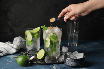 Woman making fresh mojito at table