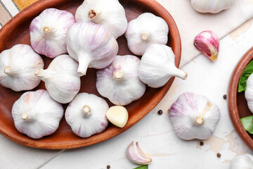 Plate with fresh garlic on light background