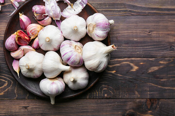 Plate with fresh garlic on wooden background