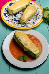 Stuffed zucchini with tuna and melted cheese on turquoise background
