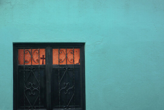 Door with Catholic cross of a bright turquoise Mexican house