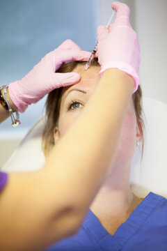 Woman recieving anti-aging injections in her forehead.
