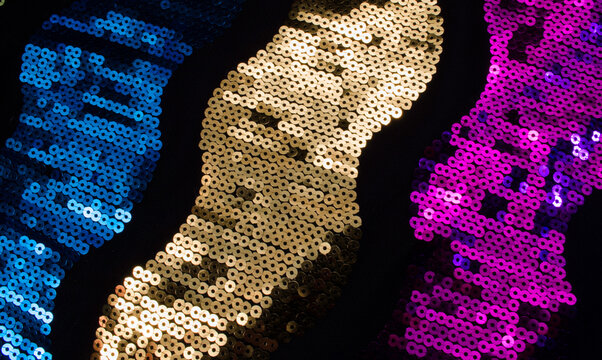 closeup macro of colored sequins forming a pattern of colored bands