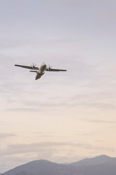 Propeller plane taking off with colorful sky and mountains