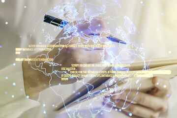 Multi exposure of abstract software development hologram with world map and man hand writing in notebook on background, global research and analytics concept
