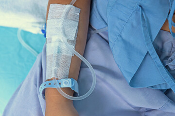 The drip-feed attached to patient's arm in hospital. Selective focus.