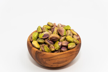 Pistachios nuts seed in a wooden bowl on white background