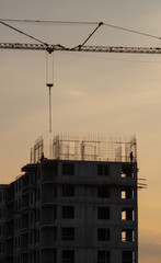 Fototapeta na wymiar Silhouettes of tower cranes against the evening sky. House under construction. Industrial skyline.