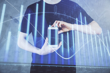 Double exposure of man's hands holding and using a digital device and forex graph drawing. Financial market concept.