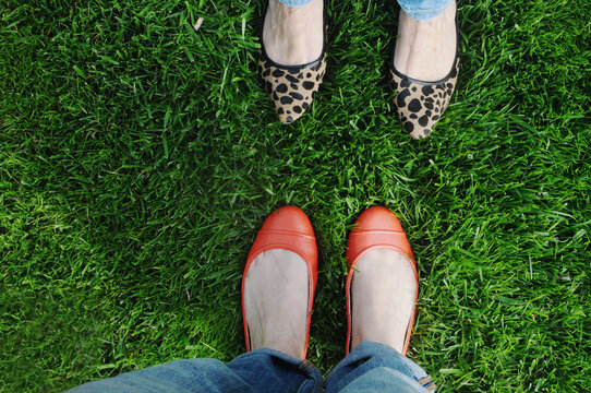 Two pairs of female feet wearing flat shoes