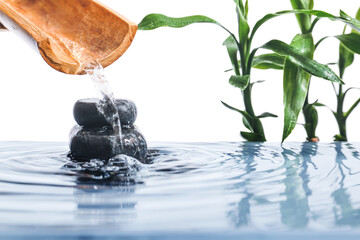 Stack of spa stones and bamboo in water on white background