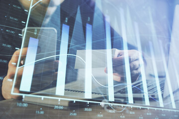Fototapeta premium Double exposure of man's hands holding and using a phone and financial graph drawing. Analysis concept.