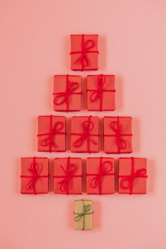 Simple gifts shaped like Christmas tree on pink background