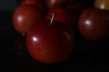 Closeup of fresh red juicy plums on the basket with droplets of water on a black background. Closeup shot of Satsuma red plums