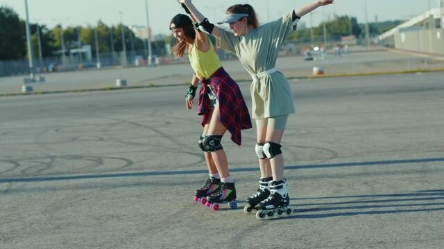 Two young pretty girls rolling skating outdoors having fun sport street legs friends rollerblading activity slow motion