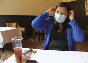 Latin adult woman with protection mask in restaurant with drink and food, new normal covid-19