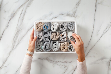 Woman hands placing organizer drawer divider with full of folded underwears and socks.