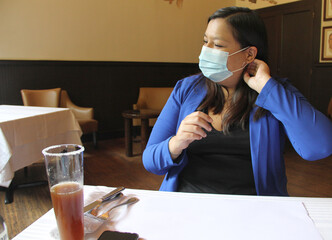 Latin adult woman with protection mask in restaurant with drink and food, new normal covid-19